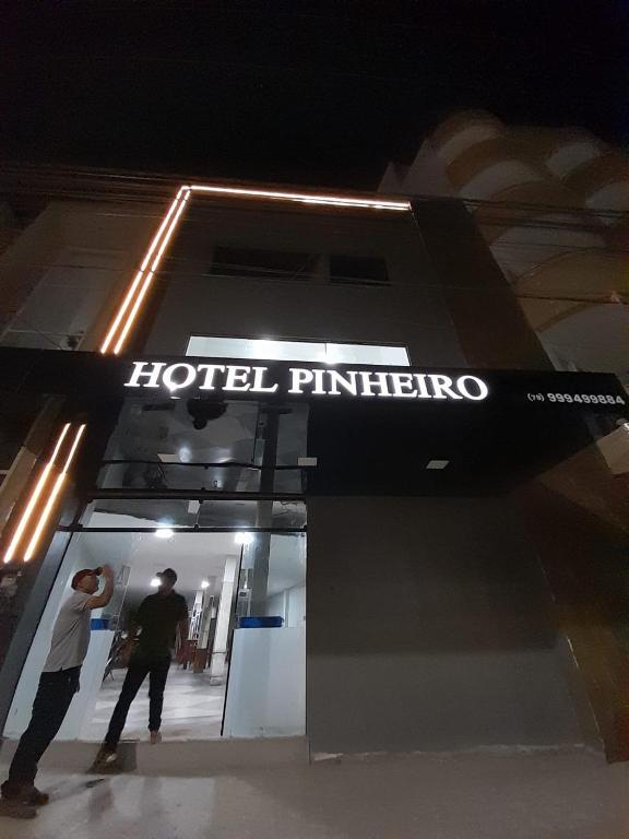 a couple of people standing in front of a store at Hotel Pinheiros in Nossa Senhora da Glória