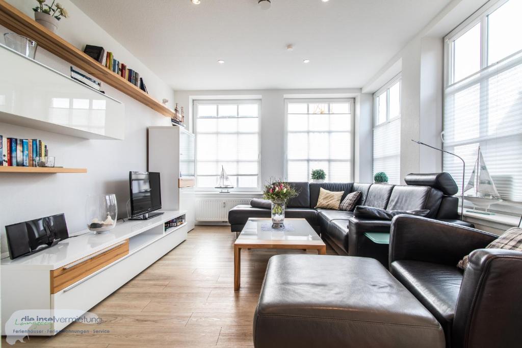 een woonkamer met een bank en een tv bij Ferienwohnung 1 im 'BÖTTCHER HUUS' in Langeoog