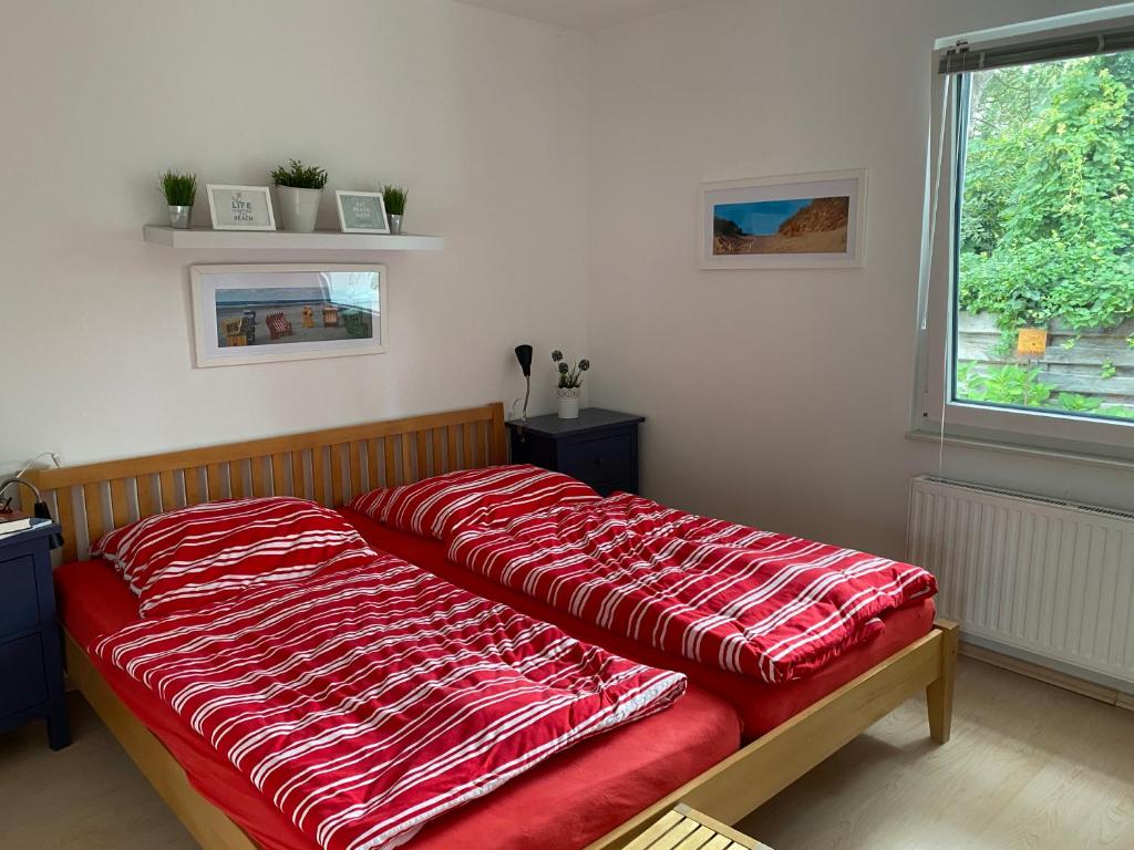 una cama roja en una habitación con ventana en Residenz 'NORDLICHT', en Langeoog