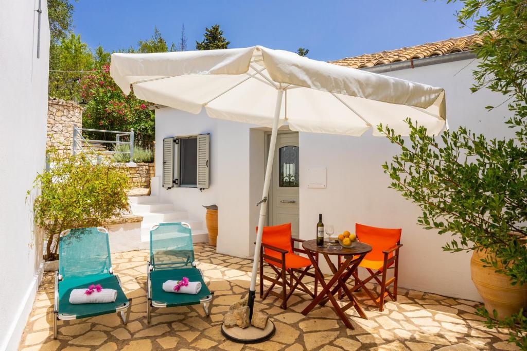 a patio with a table and chairs and an umbrella at Aimilia Cottage in Longos