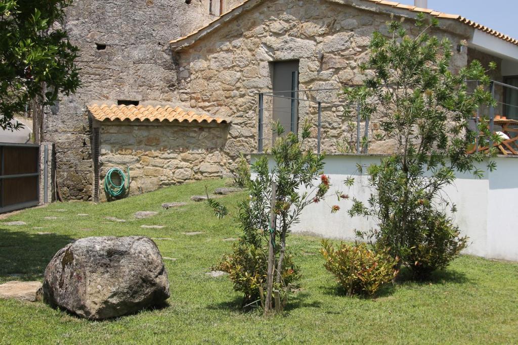 a stone house with a rock and trees in front of it at Casa do Couço in Sever do Vouga