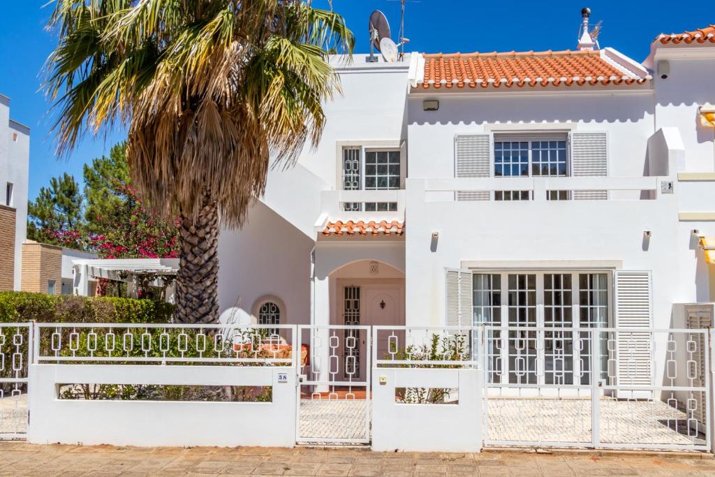 a white house with a white fence and a palm tree at Villa Audiência 38 in Monte Gordo