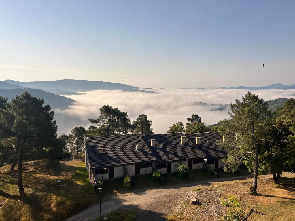 a house on a hill with clouds in the background at Village de vacances Le Serre de la Can in Saint-Germain-de-Calberte