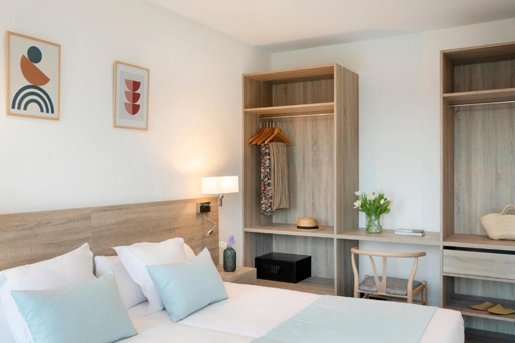 a bedroom with a white bed and a chair at Aparthotel Marina Drach in Porto Cristo