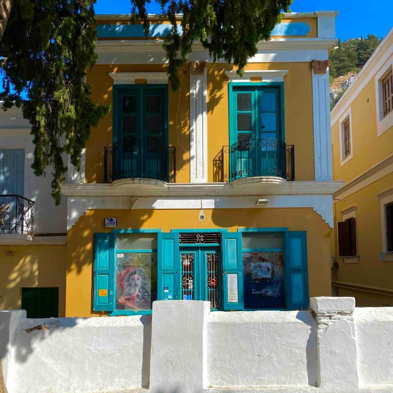 a yellow and blue building with blue doors and windows at Vavana Studios in Symi