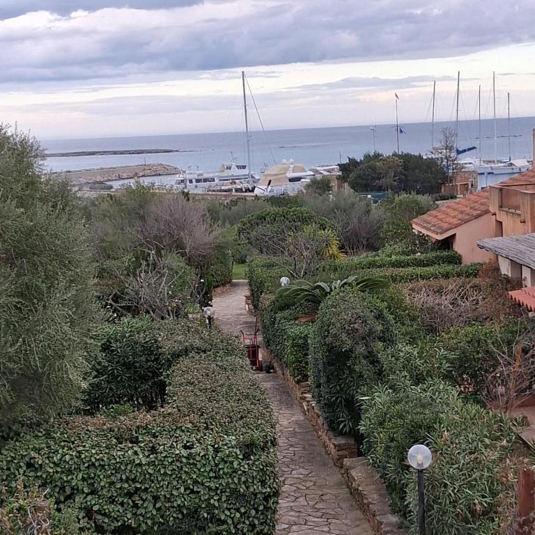 a walkway through a garden with a view of the ocean at Ottiolu House villa 50m from beach in Porto Ottiolu