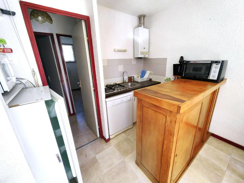 une petite cuisine avec un micro-ondes et une cuisinière dans l'établissement Villa Mitoyenne avec Terrasse, Piscine et Parking à Proximité de la Plage et du Centre - FR-1-607-27, au Cap d'Agde