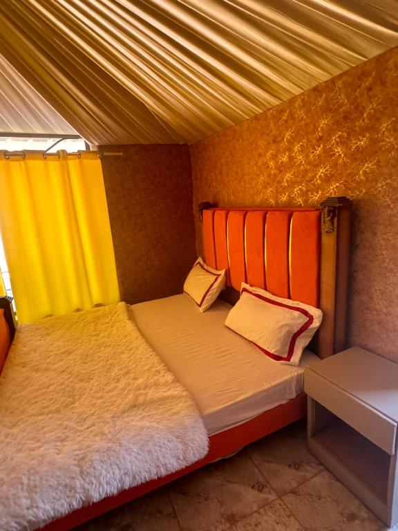a bedroom with two beds with orange and yellow curtains at Rayyan Bedouin life camp in Wadi Rum