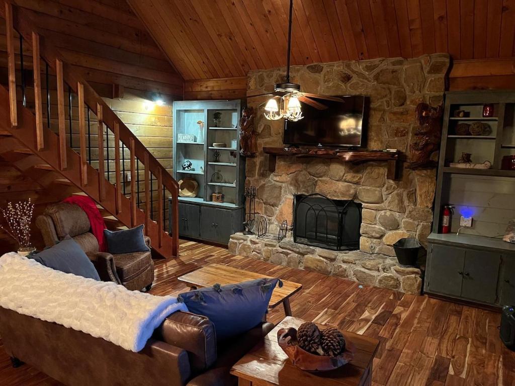 ein Wohnzimmer mit einem Sofa und einem Steinkamin in der Unterkunft Luxury Cabin HotTub, Hiking, Fire Pit, Game Room in Ellijay
