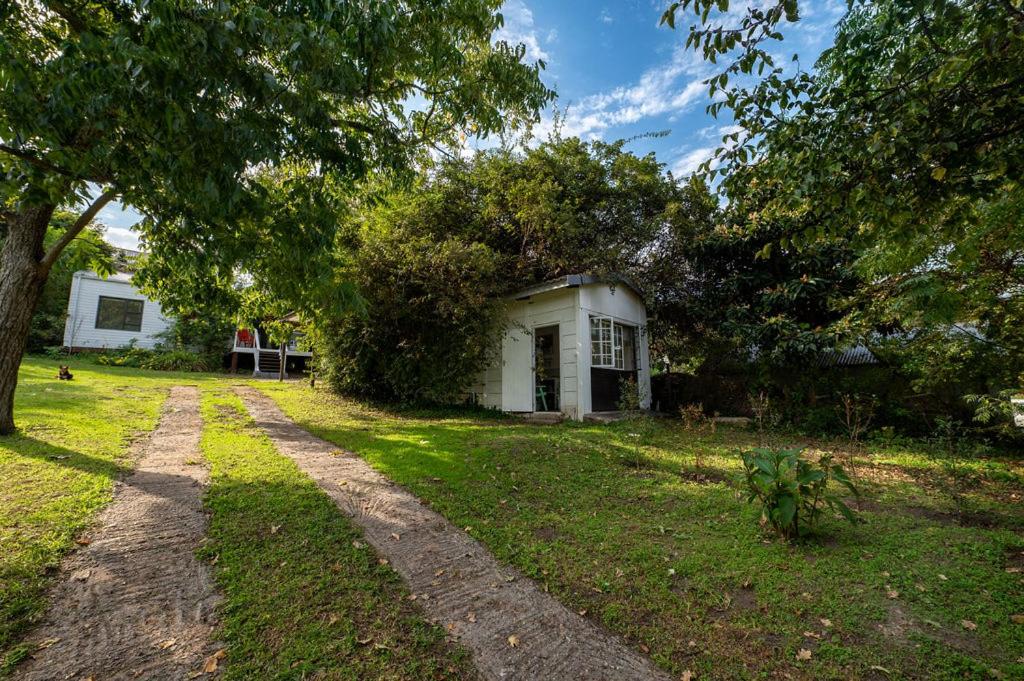 una casa con un árbol y un camino de tierra en Hillside Tiny House, en Knysna