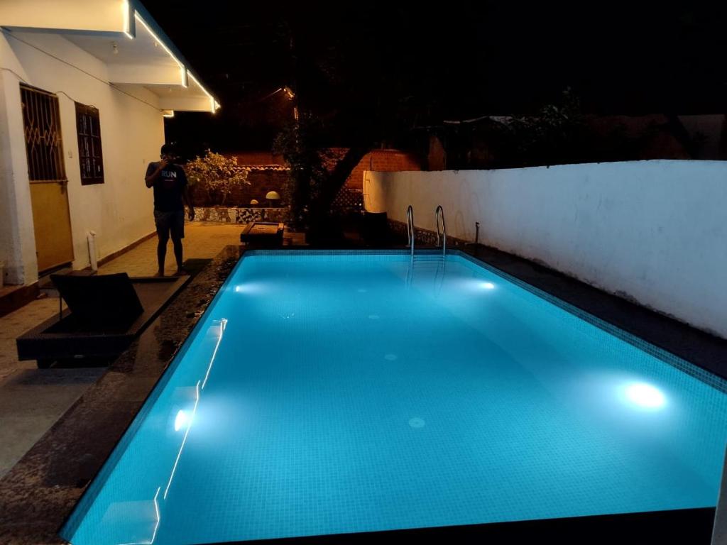 a swimming pool at night with a man standing next to it at Calangute Rocks Inn in Calangute