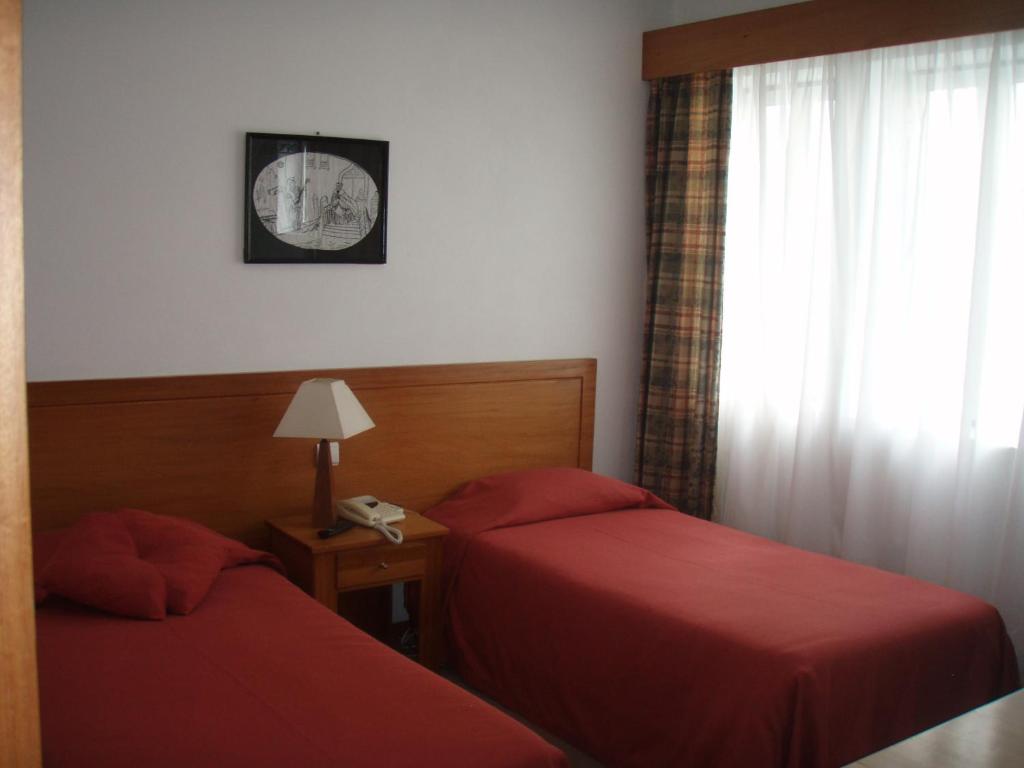 プライア・ダ・ヴィトーリアにあるHotel Residencial Ermida dos Remédiosのベッド2台と窓が備わるホテルルームです。