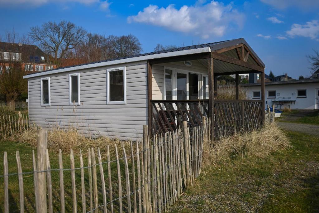 une petite maison blanche derrière une clôture en bois dans l'établissement Ferienpark Süderstapel - Eiderlodge 1, à Süderstapel