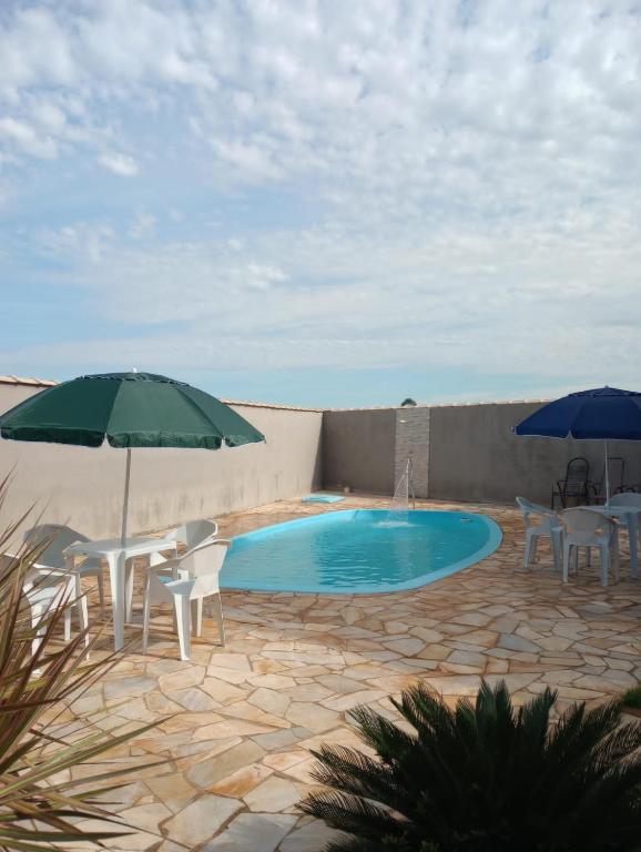 a swimming pool with chairs and umbrellas at Canto dos Pássaros in Igarassú