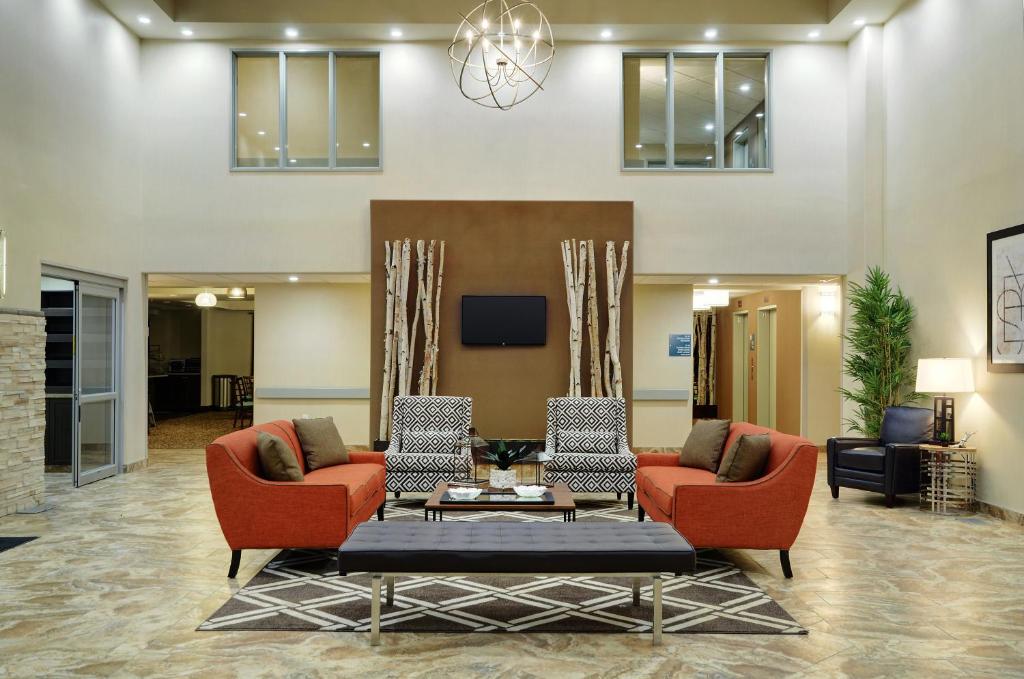 a lobby with two chairs and a couch and a table at Pomeroy Inn and Suites Vermilion in Vermilion