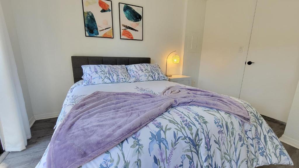 盖恩斯维尔Discover Luxury Condo Steps Away from Celebration Pointe and I-75!的一间卧室配有一张带紫色棉被的床