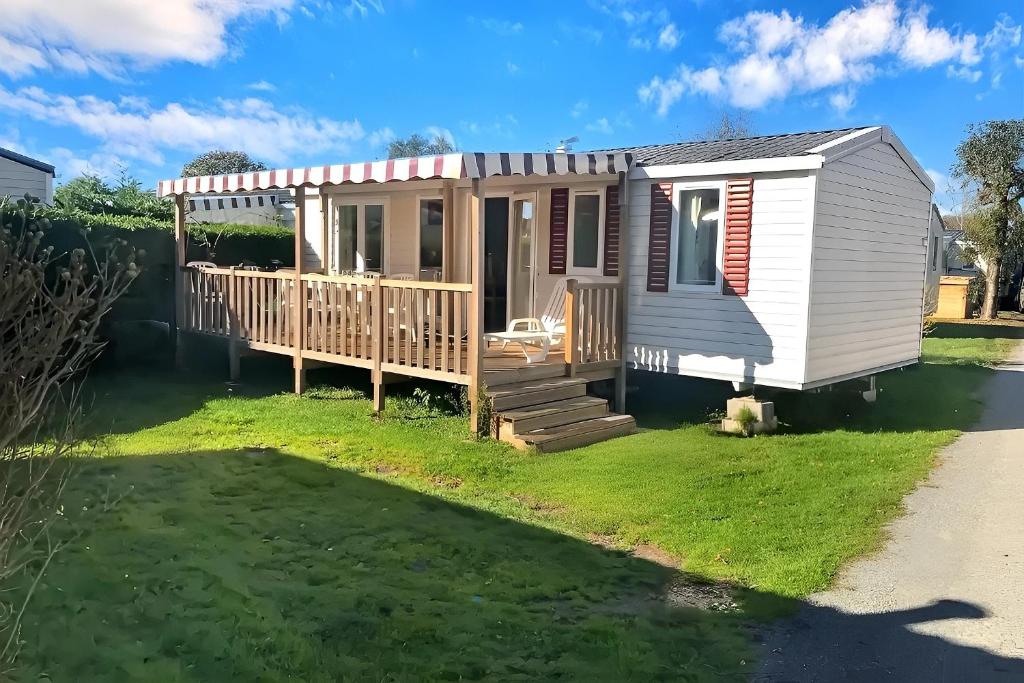 a tiny house with a porch and a deck at Mobil home 3 chambres, empl K079, les charmettes in Les Mathes