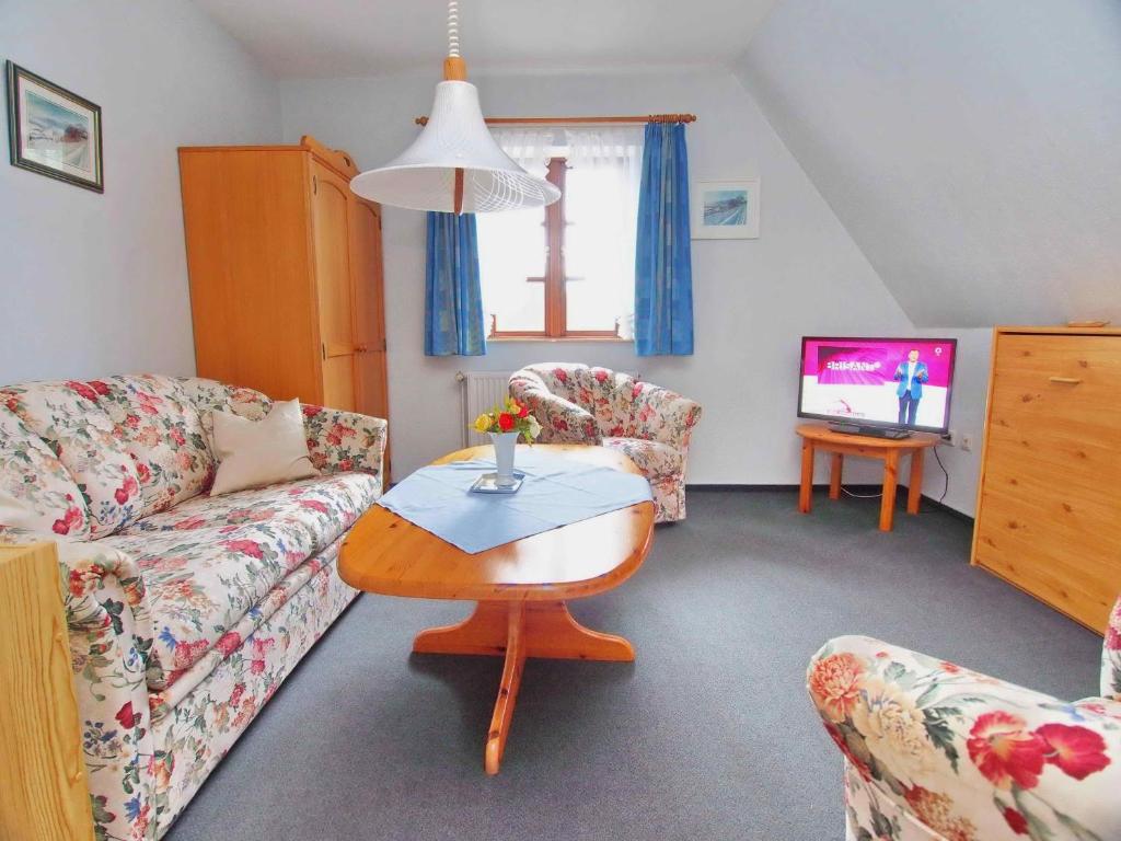 a living room with a couch and a table and a tv at Gaestehaus-Bruhn-5 in Alkersum