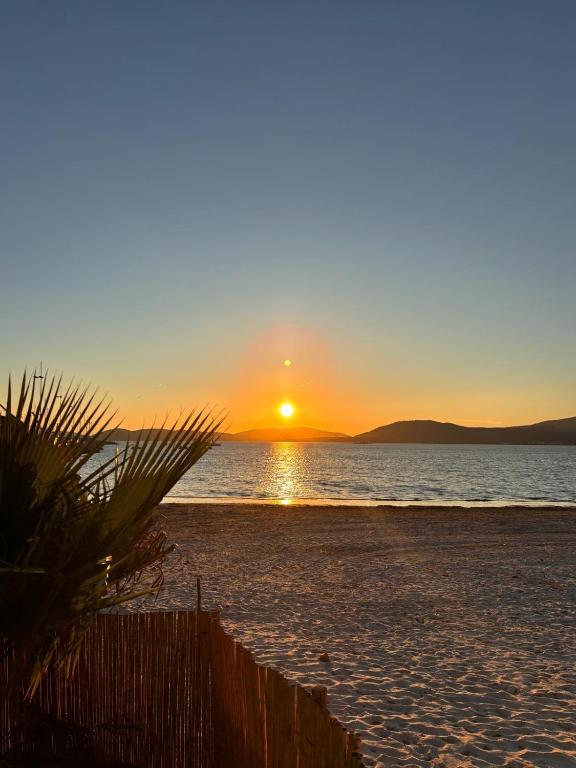 a sunset on the beach with the sun setting at Penthouse Apartment A due passi dal Mare in Alghero