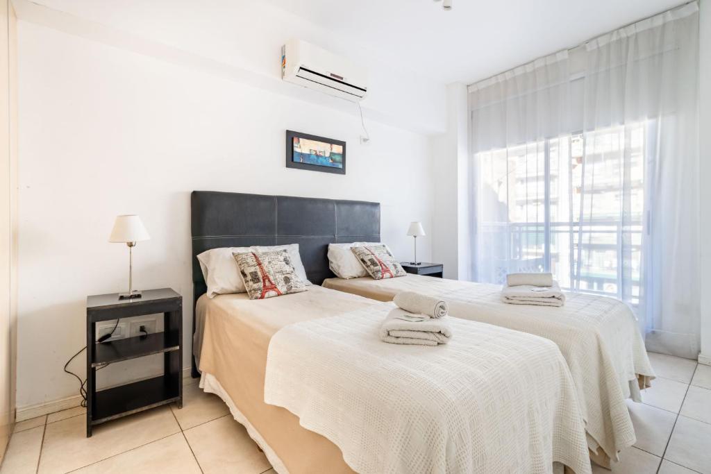 a bedroom with two beds with white sheets and a window at Apartments Babel Recoleta in Buenos Aires