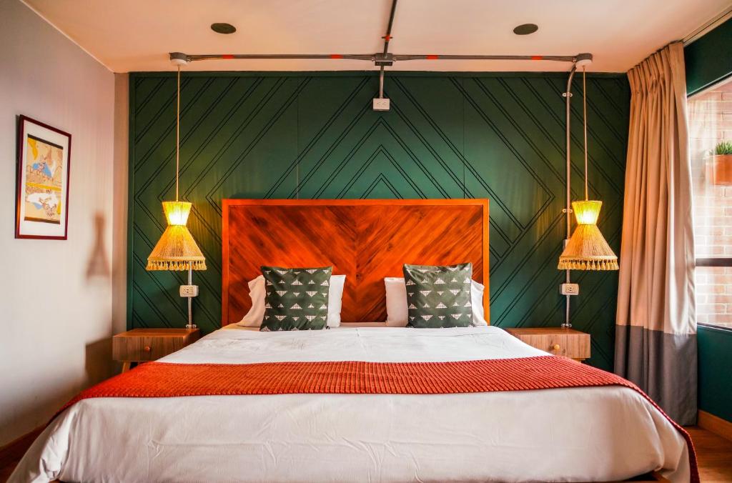 a bedroom with a large bed with green walls at ILAR 74 Coliving & Hotel Avenida Chile Bogota in Bogotá