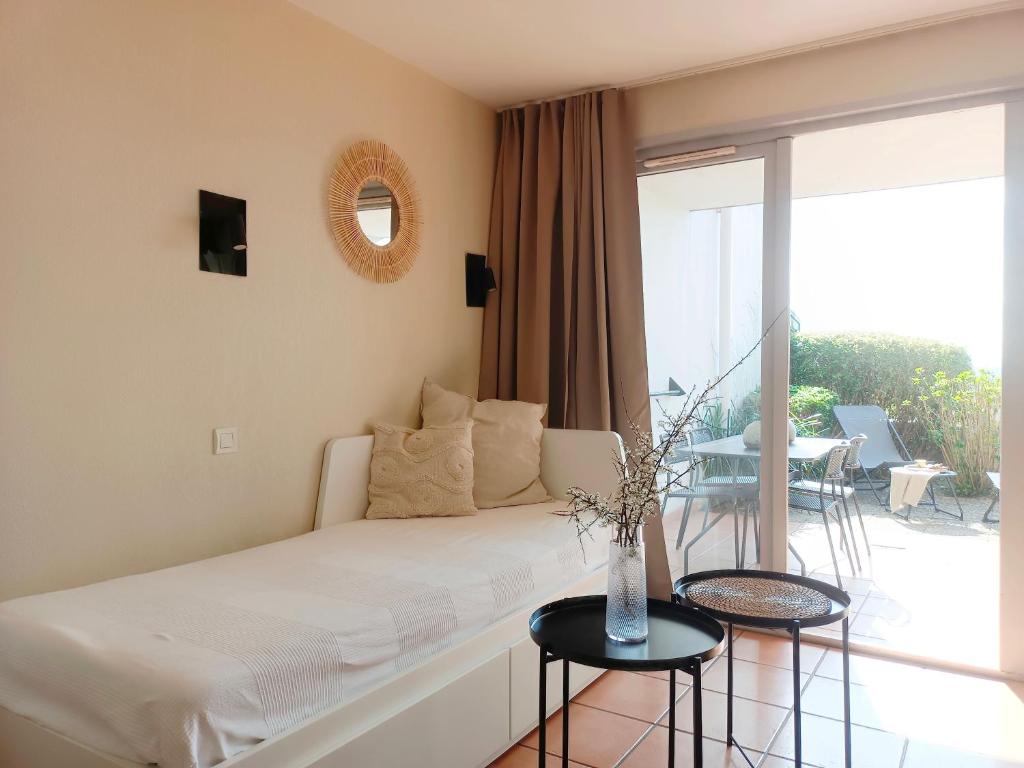 a living room with a white couch and a balcony at T1 Bis avec piscine vue golf et montagnes in Arcangues