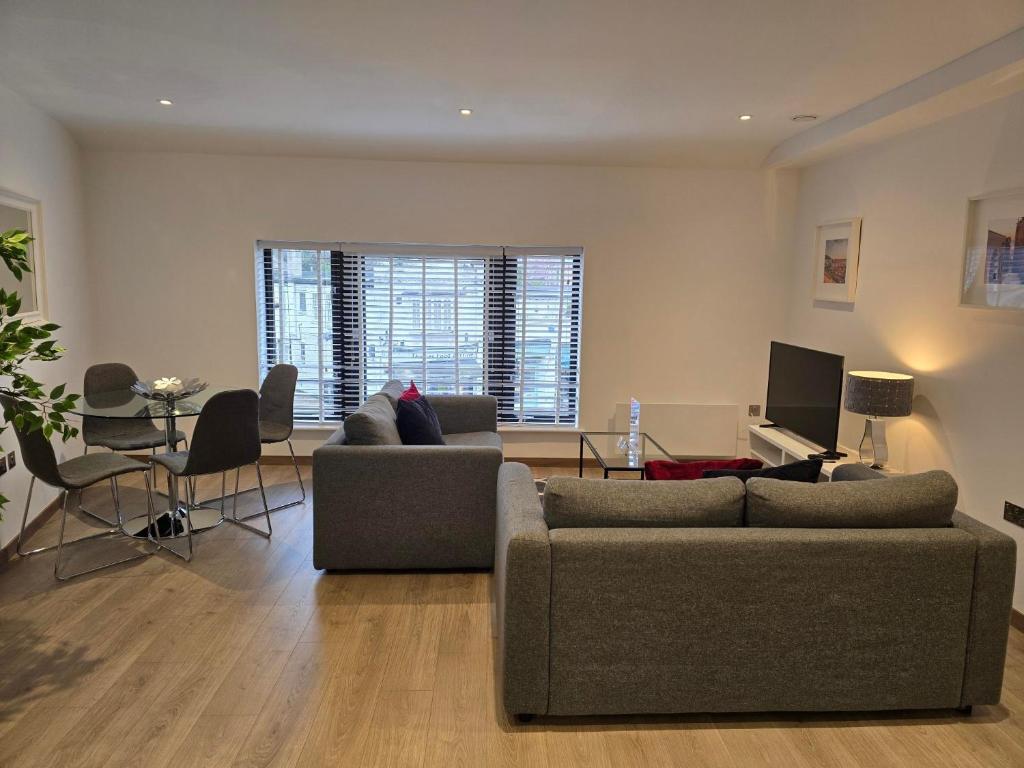 a living room with a couch and a table and a television at Roomspace Serviced Apartments - Harvest Lane in Thames Ditton