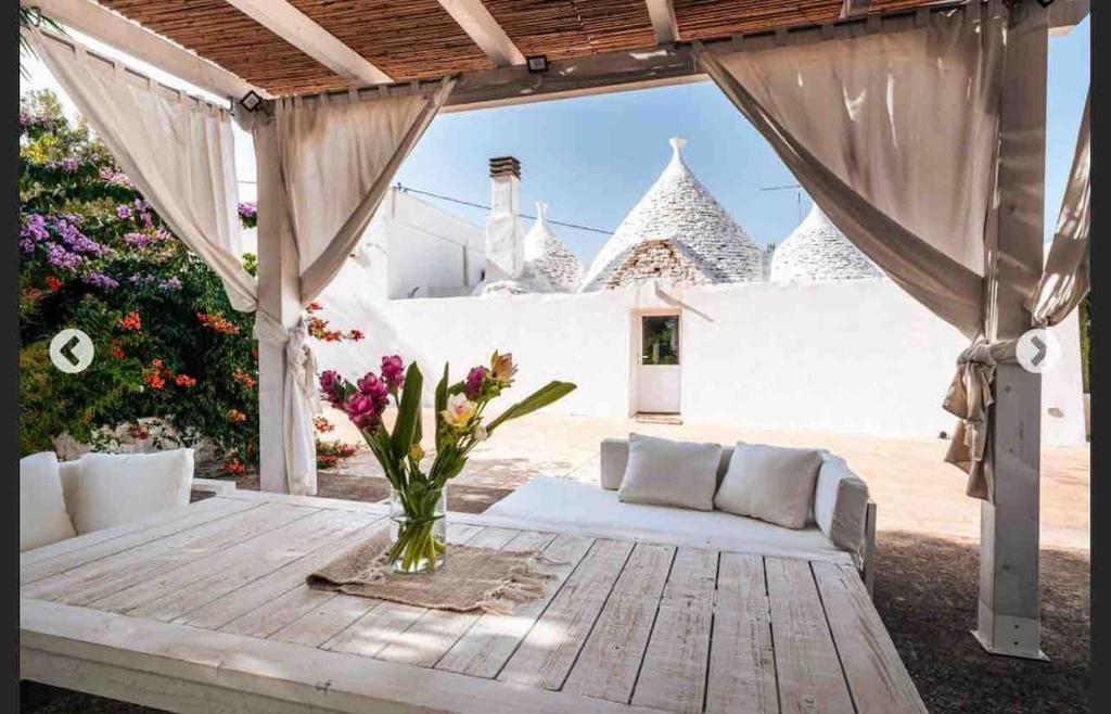a patio with a couch and a table with flowers at Modern trulli with a beautiful new pool in Ceglie Messapica