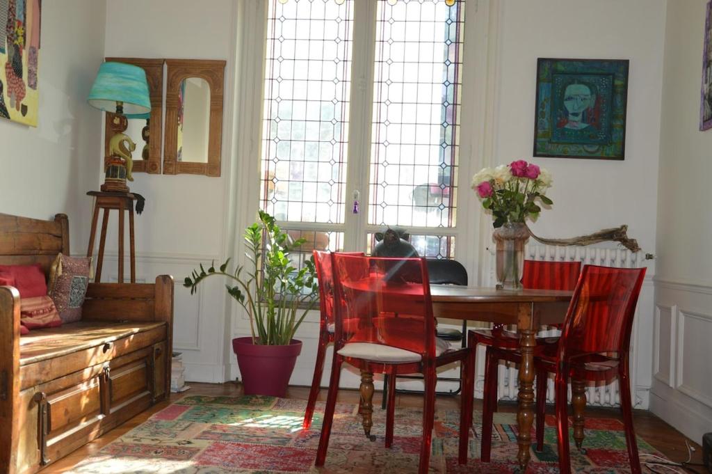 une salle à manger avec une table et des chaises rouges dans l'établissement Appartement village Jourdain, à Paris