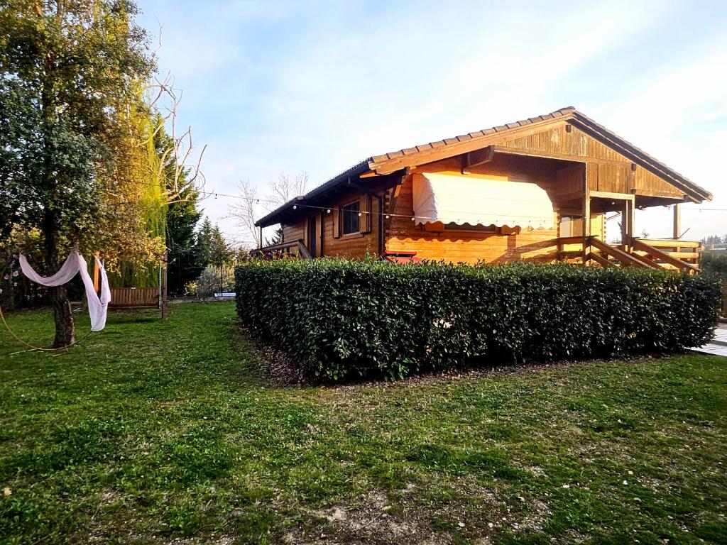 una cabina di legno in un cortile accanto a una siepe di Chalet Collalto con Piscina a Cerratina