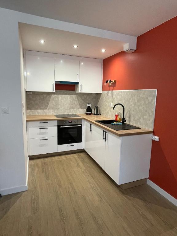 une cuisine avec des placards blancs et un mur rouge dans l'établissement appartement cosy à 100m de la mer !, à Cucq