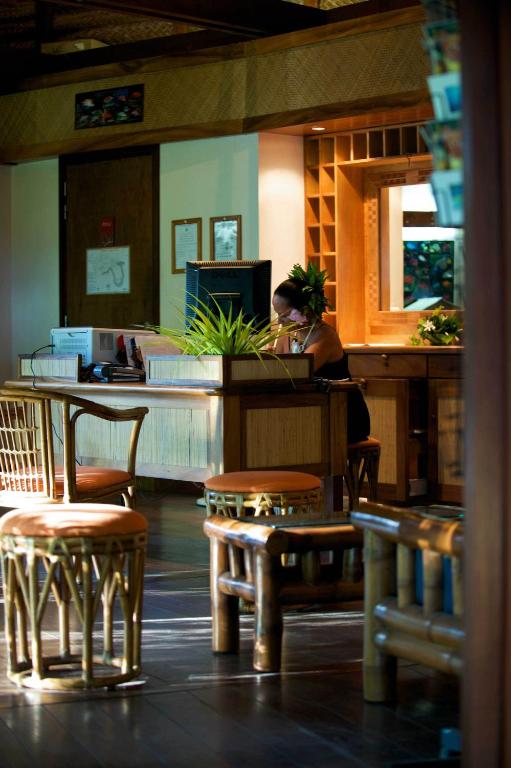a restaurant with tables and stools and a counter at Maitai Rangiroa in Avatoru