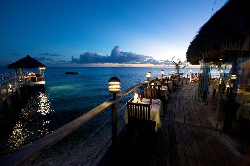 a restaurant with a view of the ocean at night at Maitai Rangiroa in Avatoru