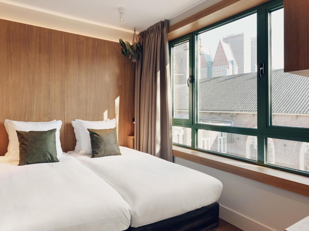 a bedroom with a large bed and a large window at Townhouse Den Haag in The Hague