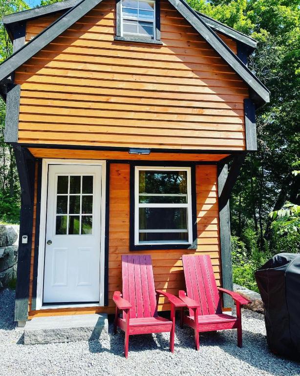two red chairs in front of a tiny house at Off Grid Wildwood Bunkies in Bailieboro