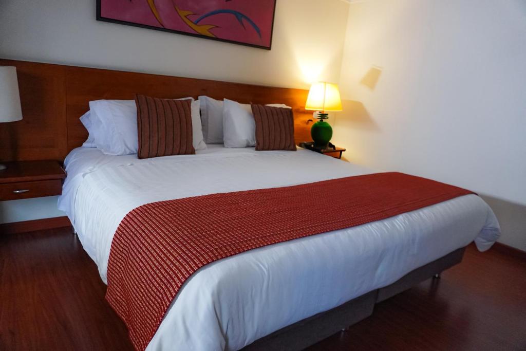 a bedroom with a large bed with a red blanket at Corferias ILAR Coliving & Hotel Embajada Americana in Bogotá