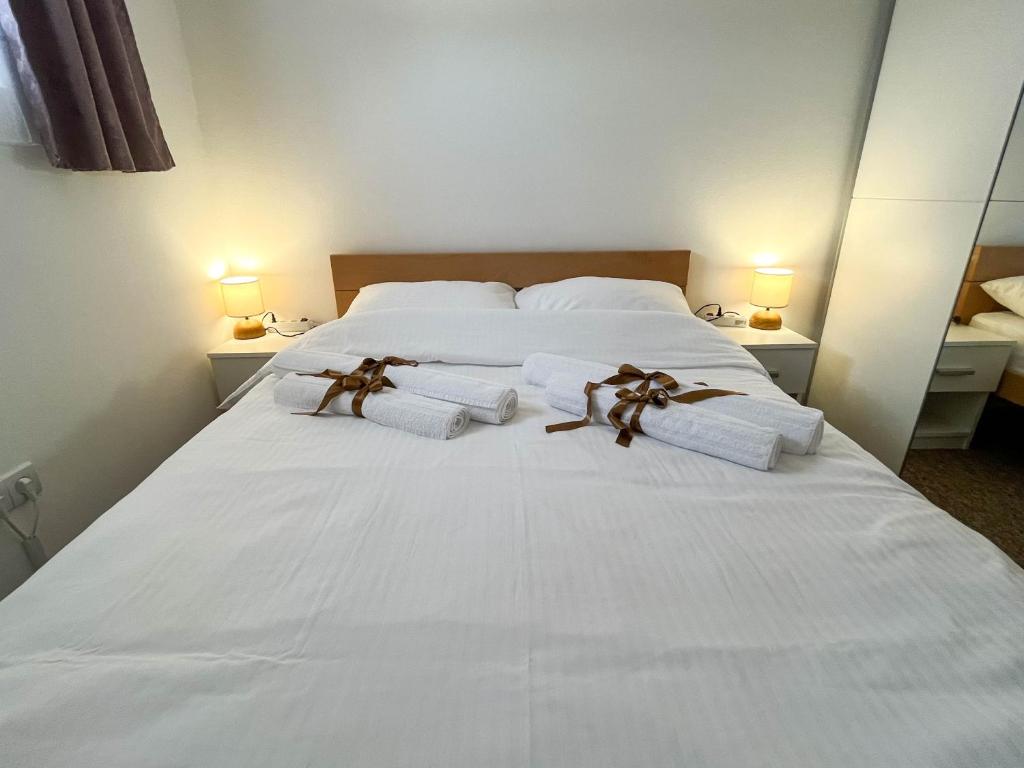 uma cama branca com toalhas e arcos em Apartmani Moslavina, free big parking, workspace, crib, satin cotton sheets em Kutina