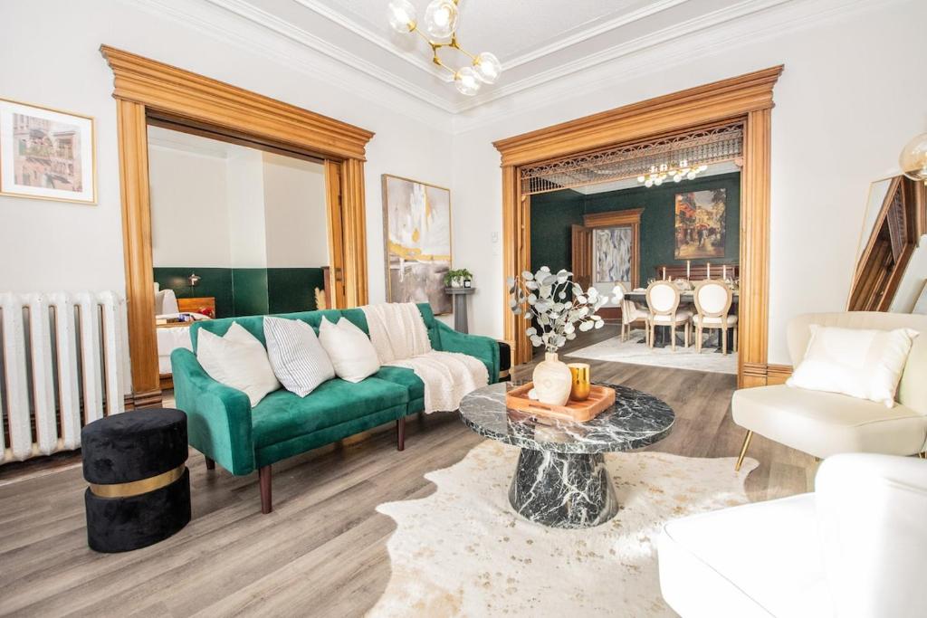 a living room with a green couch and a table at Elegant Escape, Modern Luxe in Historic Suite in Saint John