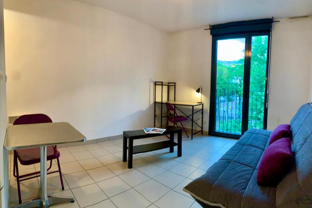 un salon avec un canapé bleu et une table dans l'établissement Résidence Noisica, à Saint-Étienne