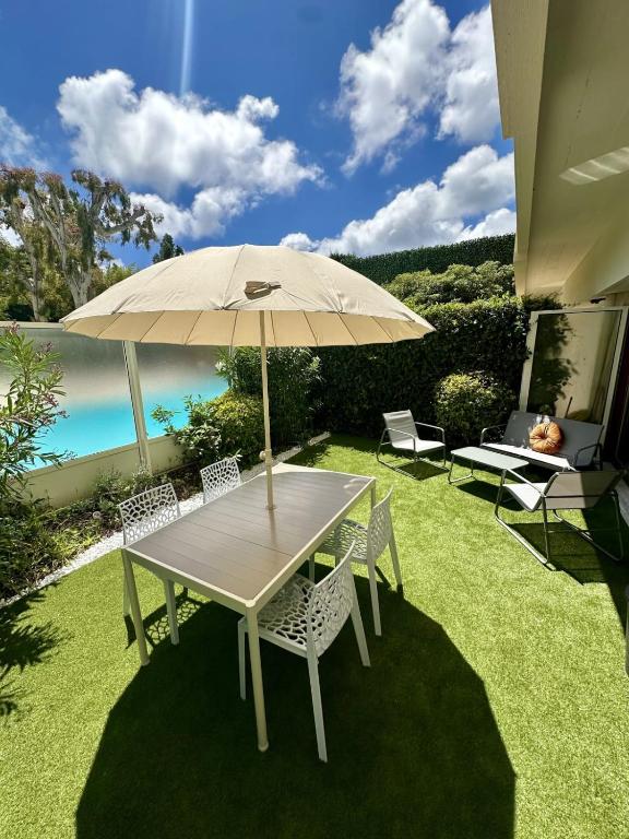 une table et des chaises avec un parasol sur l'herbe dans l'établissement T2 close to the beach, à Antibes