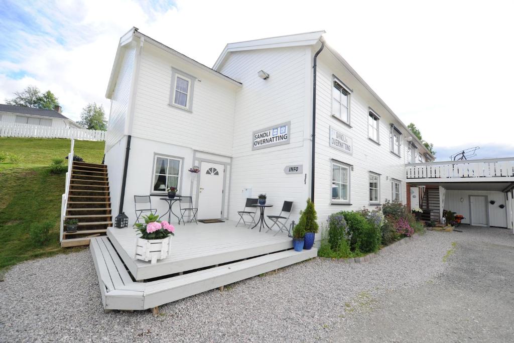 ein weißes Haus mit einer Veranda und einer Terrasse in der Unterkunft Sandli Overnatting in Alvdal