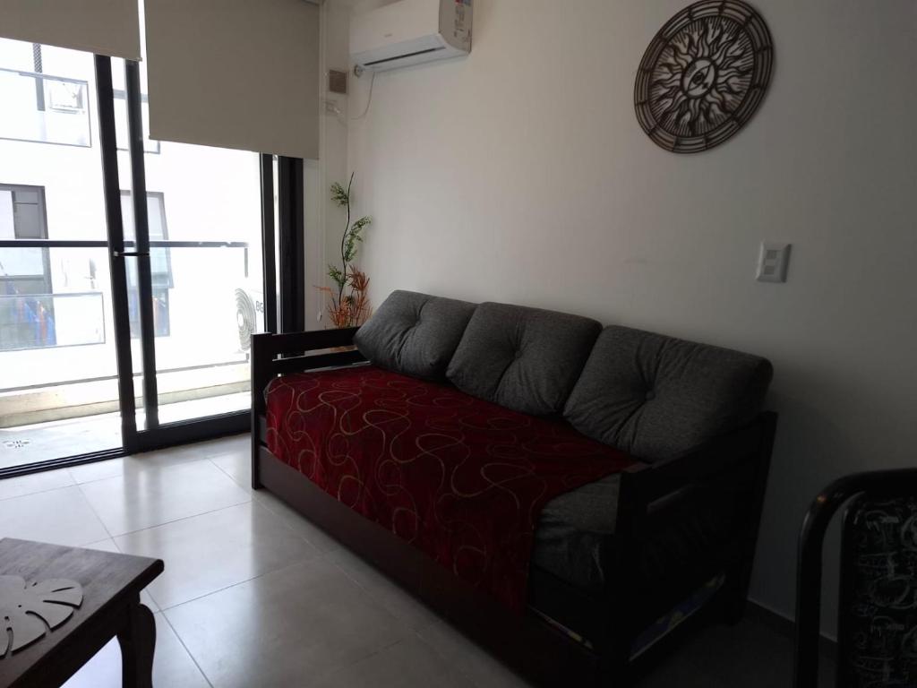 een bank in een woonkamer met een klok aan de muur bij Departamentos Céntricos Exclusivos in Villa Carlos Paz