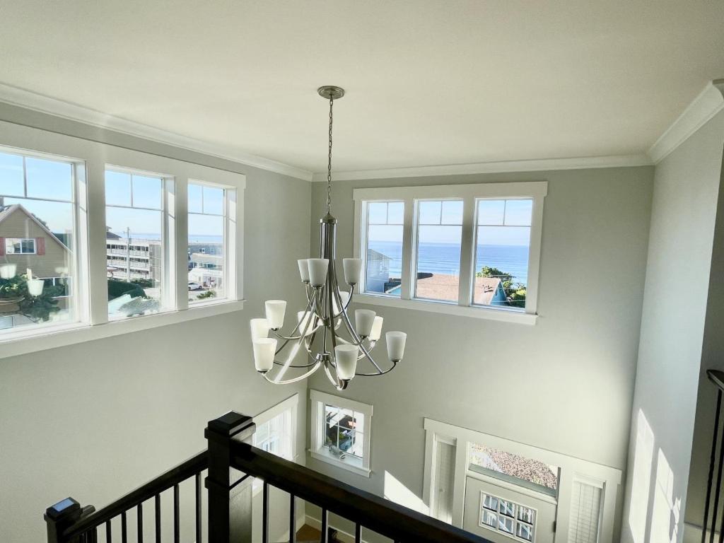 una scala con un lampadario a braccio in una stanza con finestre di Ocean Views, Spacious Getaway, 5BR, Hot Tub, Sleeps 16 a Lincoln City