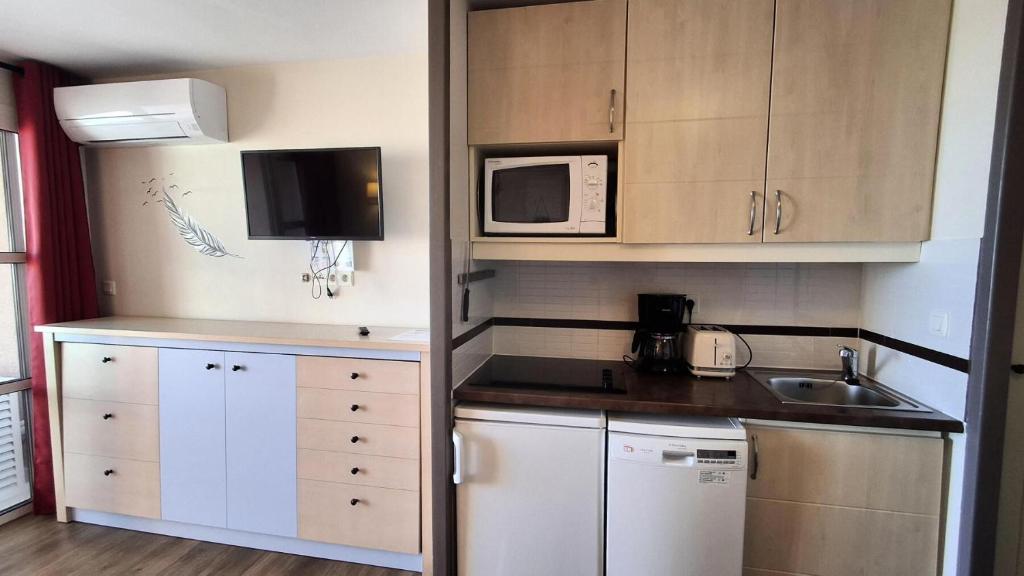 une petite cuisine avec un évier et un micro-ondes dans l'établissement Résidence le Village de Cap Esterel - maeva Home - Appartement 2 pièces 5 personnes - Sélection MAE-5754, à Saint-Raphaël