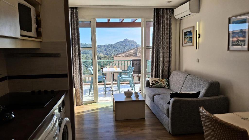 d'un salon avec un canapé et une vue sur un balcon. dans l'établissement Résidence le Village de Cap Esterel - maeva Home - Appartement 2 pièces 4 personnes - Sélection MAE-4804, à Saint-Raphaël