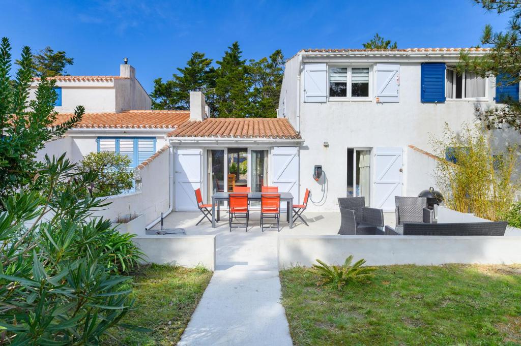 a white house with a patio with a table and chairs at Maison, 150 m de la plage, la Tresson,Noirmoutier in La Guérinière