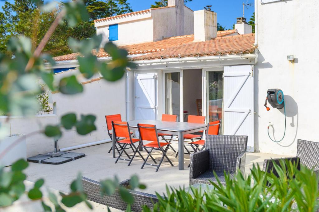 une terrasse avec une table et des chaises ainsi qu'une maison dans l'établissement Maison, 150 m de la plage, la Tresson,Noirmoutier, à La Guérinière