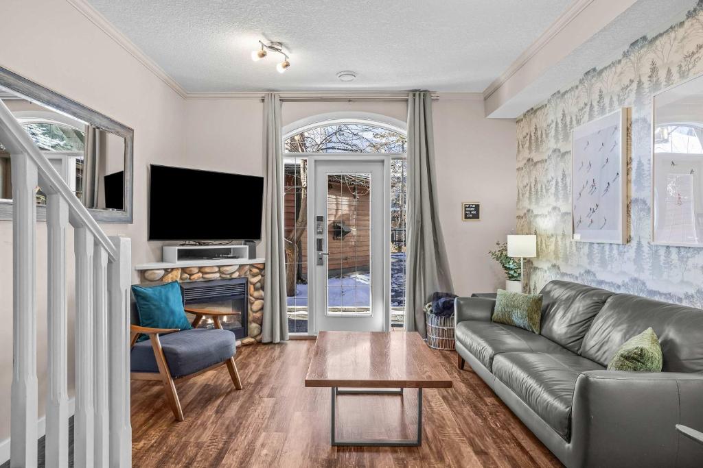a living room with a couch and a tv at Cozy Mountain Chalet at Mystic Springs with Pool & Hot Tub Access in Canmore