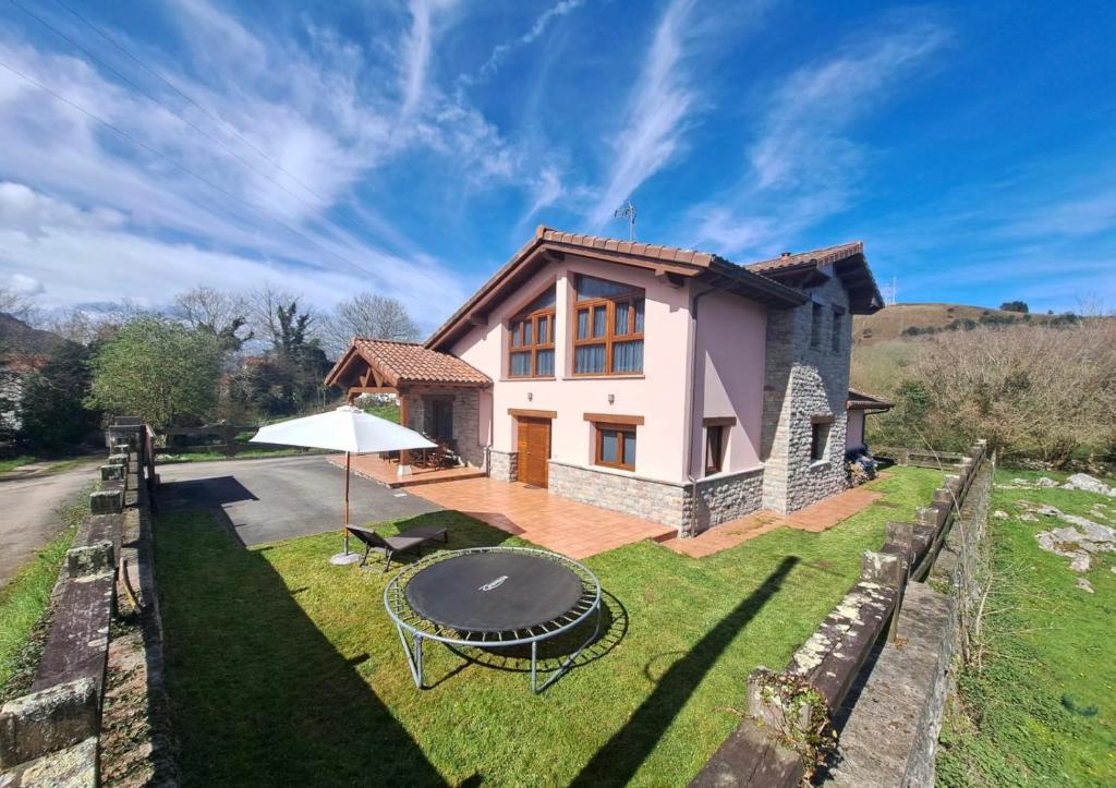 a house with a table and an umbrella at Chalet Huerta de Cañamal - Llanes in Llanes