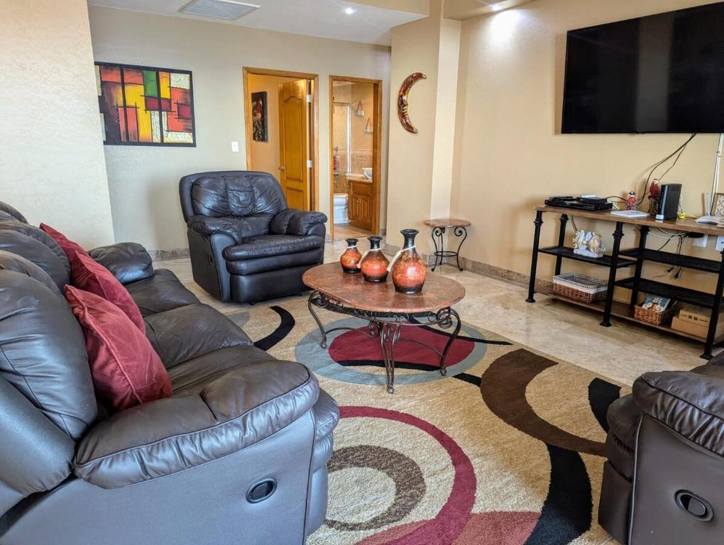 Rosarito BeachにあるDream Condo Pool, Jacuzzi, and Ocean Viewsの革張りのソファとテーブルのあるリビングルーム